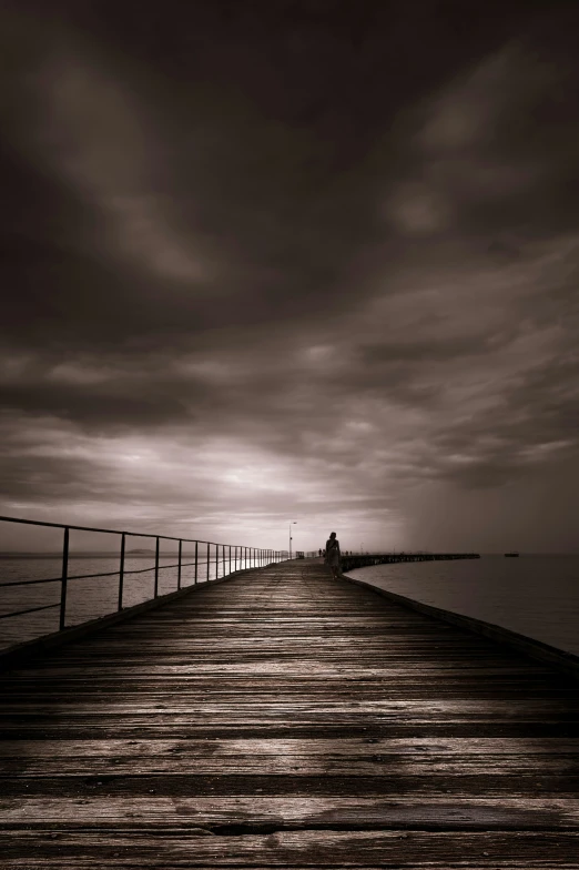 people standing on the pier by the water and one person sitting on the bench looking at the water