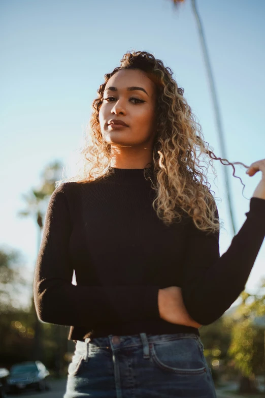 a woman with curly hair is wearing jeans