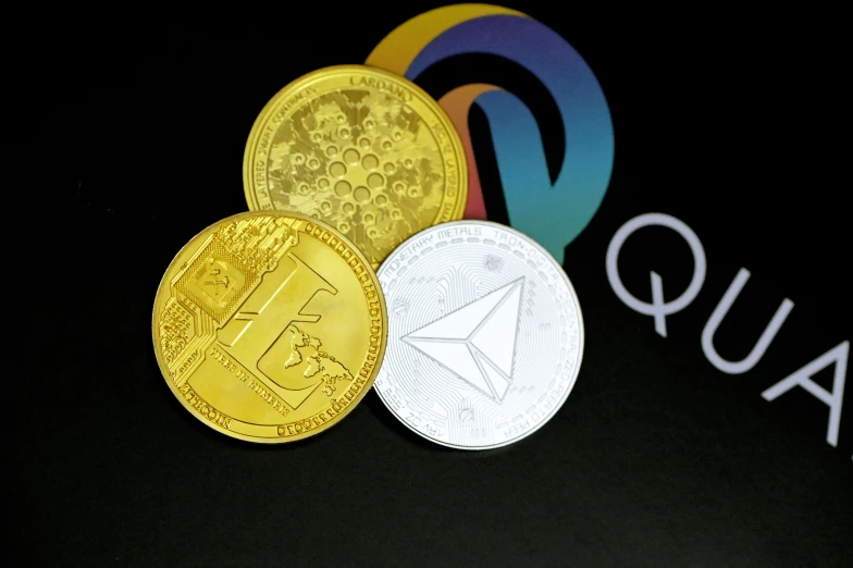 three different colored and white coins and a q logo
