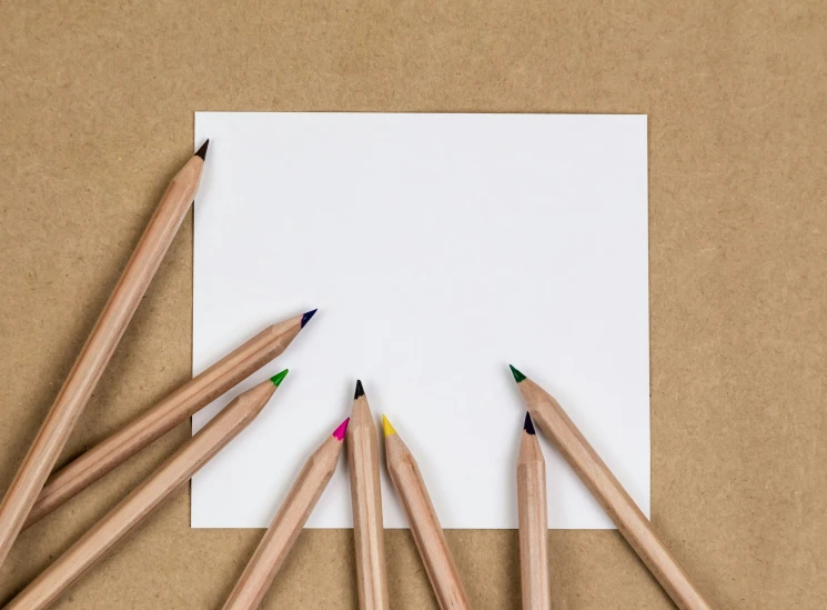 several colored pencils in front of a sheet of paper