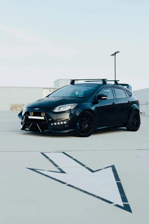 a black car with black rims parked in the parking lot