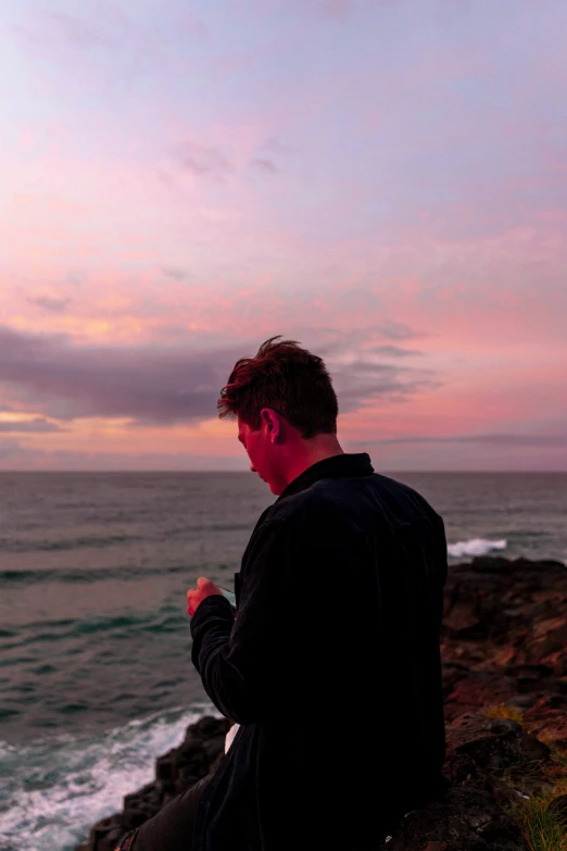 a man is sitting and praying near the ocean