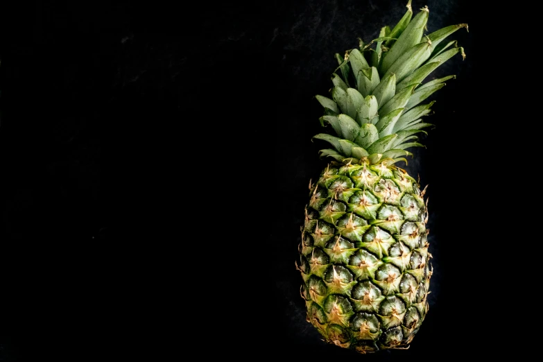 a large pineapple sitting on a table with black background