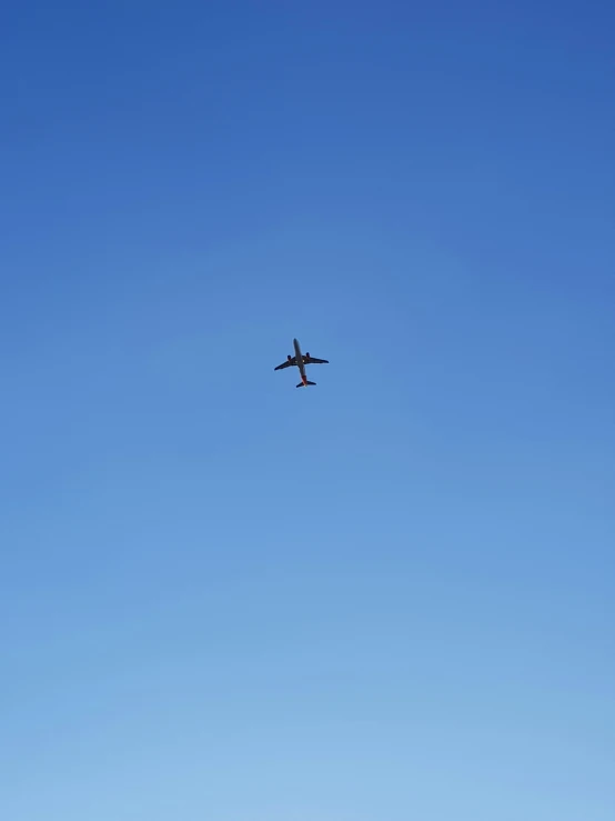 an airplane flying in the blue sky over some trees