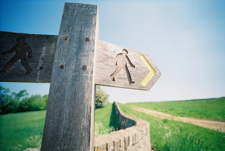 a wooden sign with a walking sign pointing in two different directions