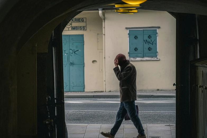 a man walking into a small, arched tunnel in the rain