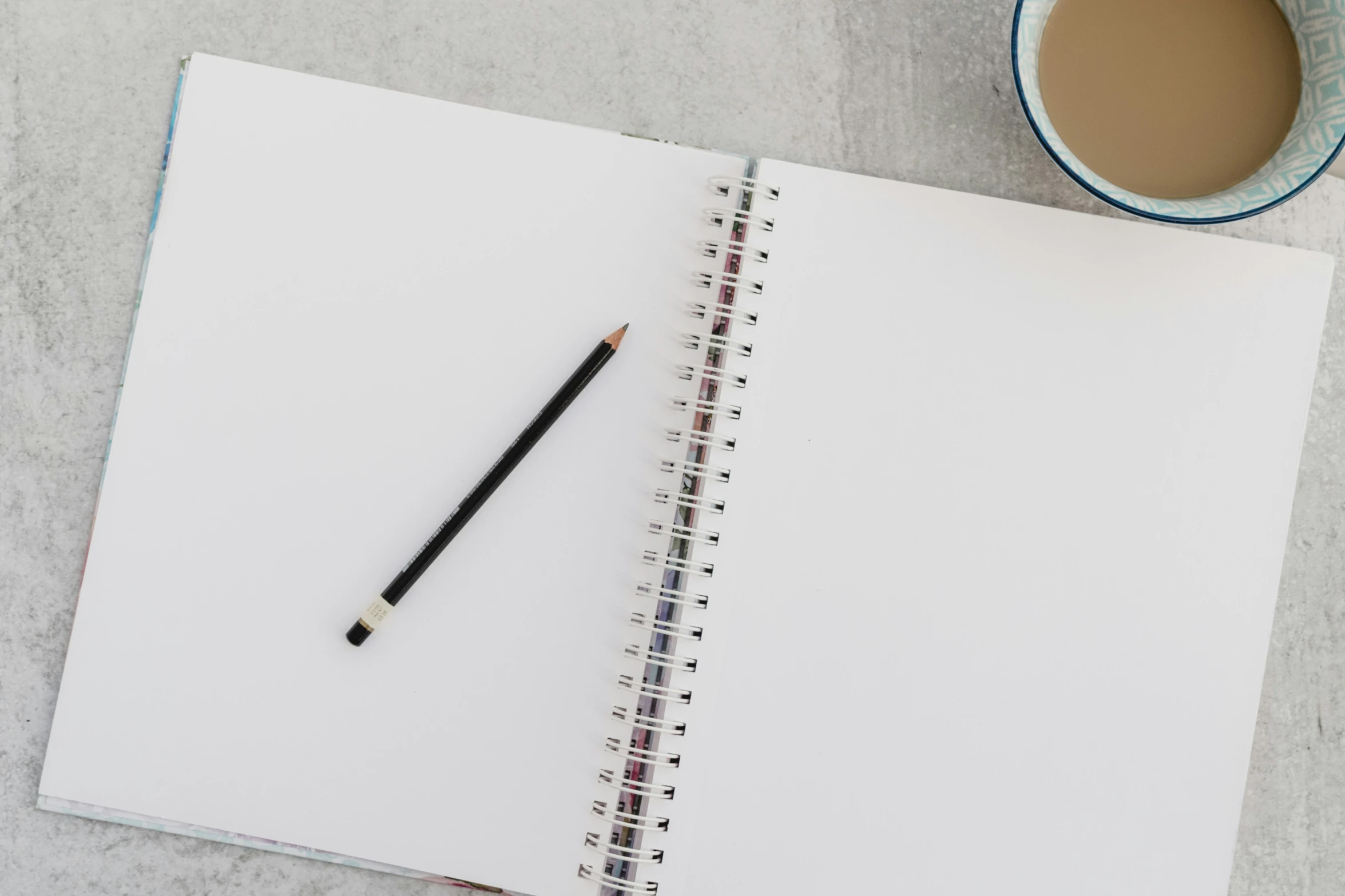 an open notebook next to a cup of coffee