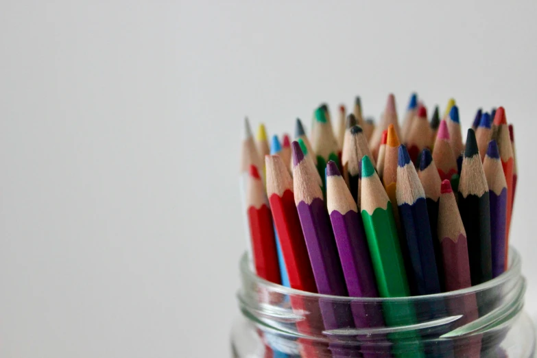 a jar of colored pencils with a reflection