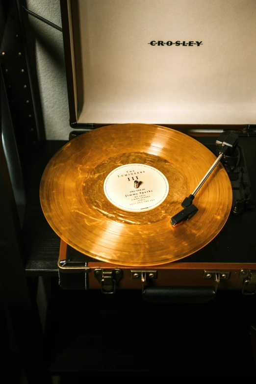 a golden record player and case sitting on a table