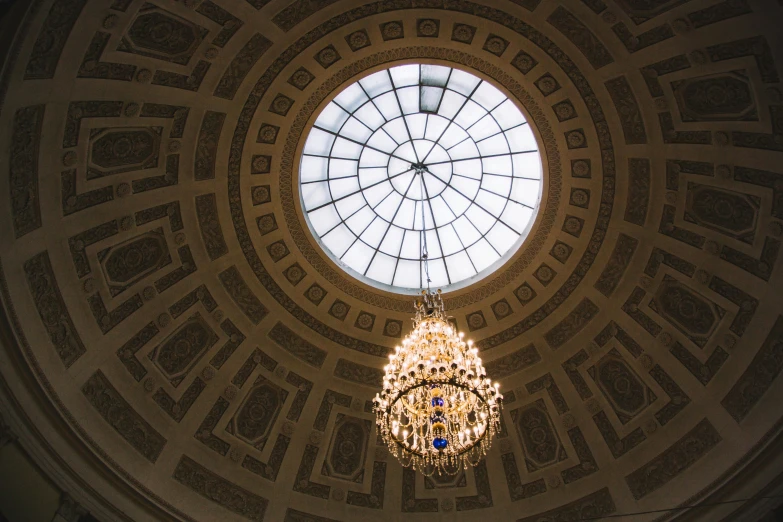 a ceiling with a circular glass and golden chandelier