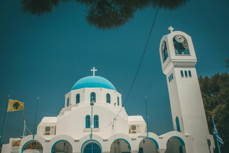 white and blue building with a cross on top and flags