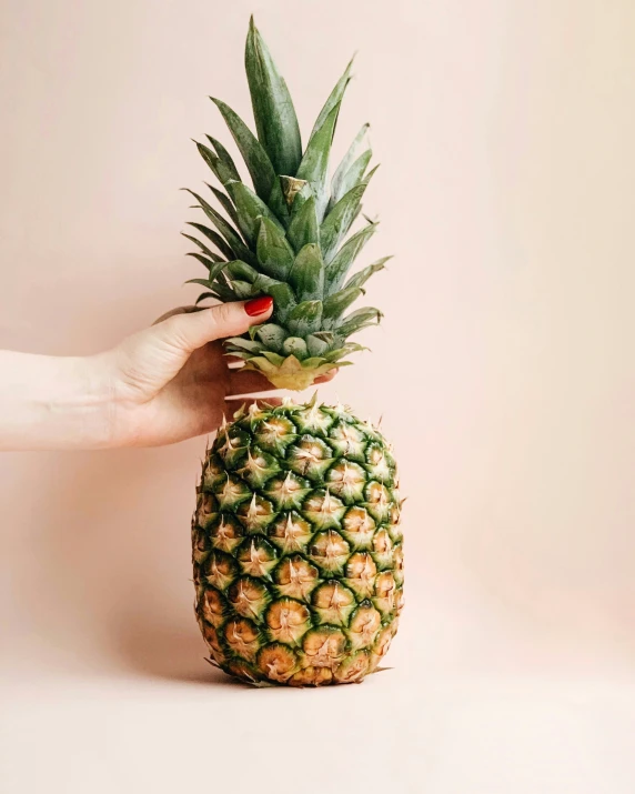 a pineapple is being held by a person's hand