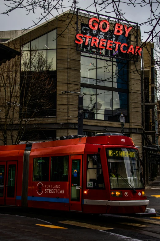 a red train is riding down the street