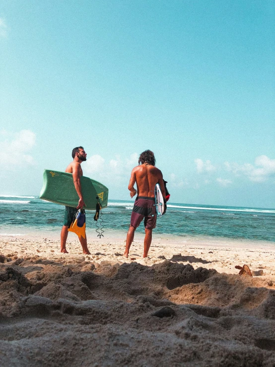 two men with surfboards walk into the ocean