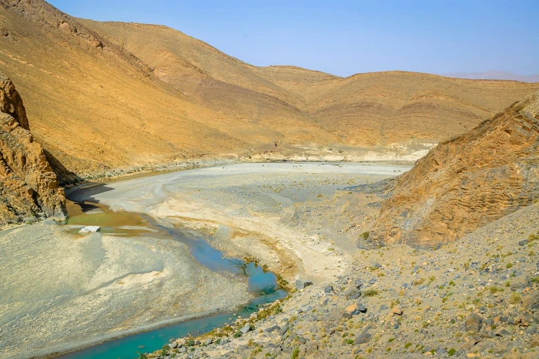 a river and hills in the desert, with blue water