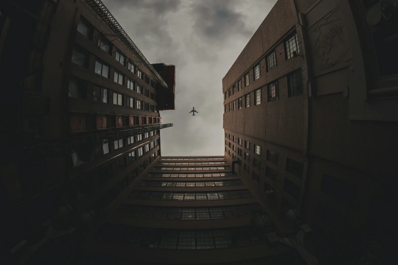 an airplane flying over building towers under a cloudy sky