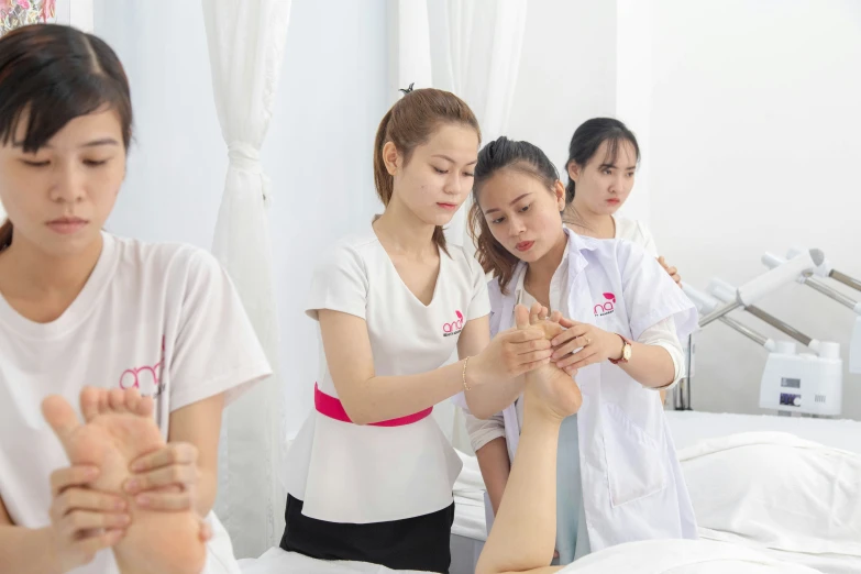 five girls stand around a person in a bed