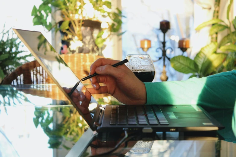 a person typing on a laptop with a cup of coffee in front of it