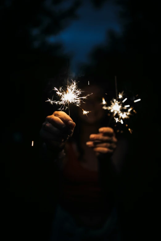 a woman holding out sparklers at night