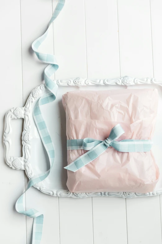 a present wrapped in light pink paper and a blue ribbon on top