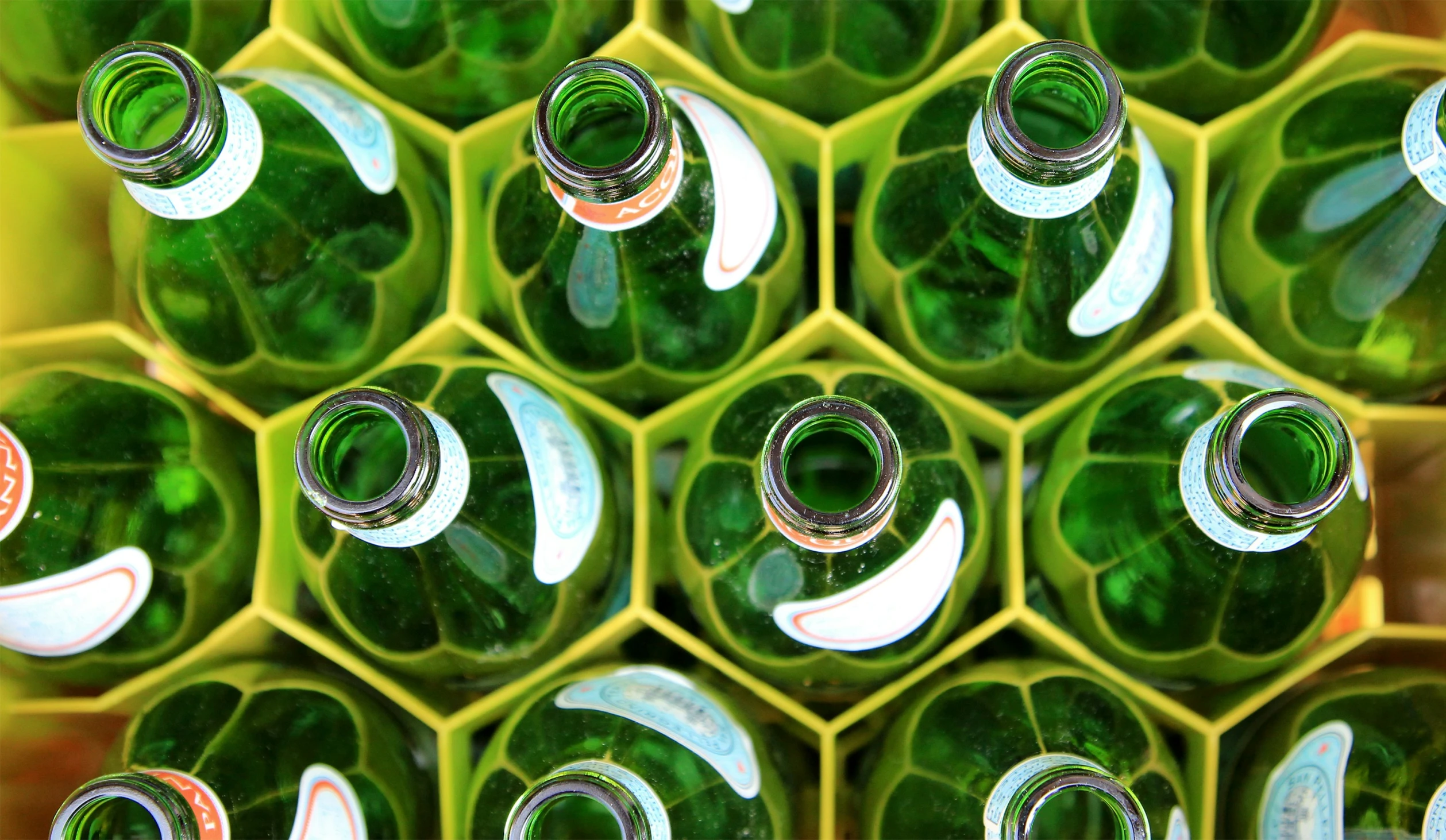 many green glass bottles are stacked and lined in rows