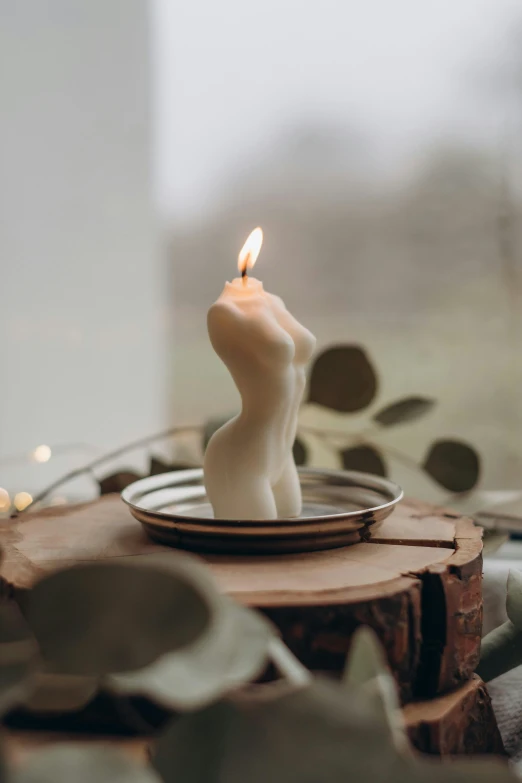 a white candle in a plate sitting on top of a wooden table