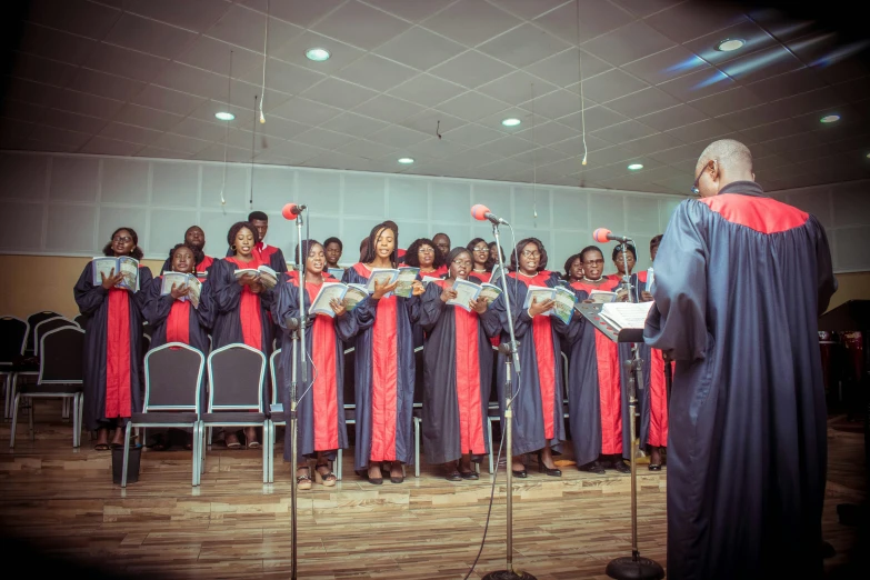 a choir of students sings with microphones while the man holds a sheet