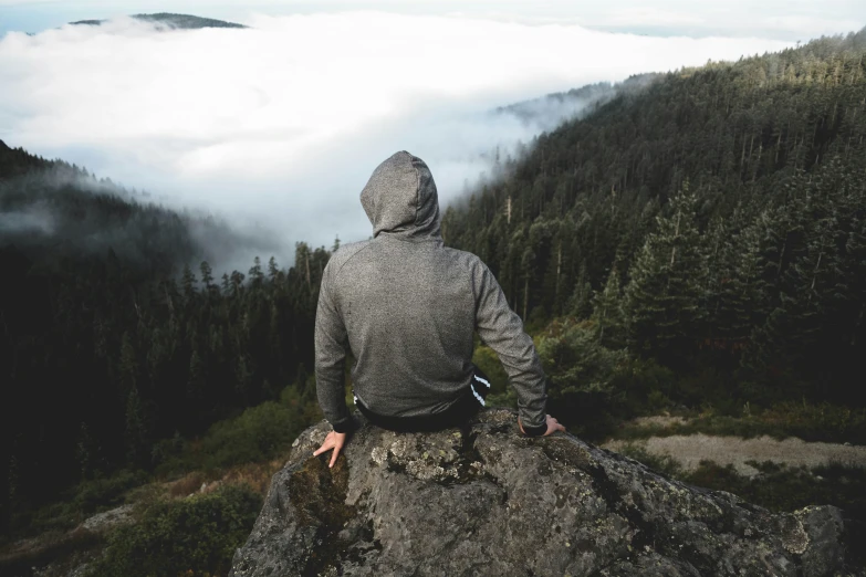 man overlooking the clouds, trees and valley in winter