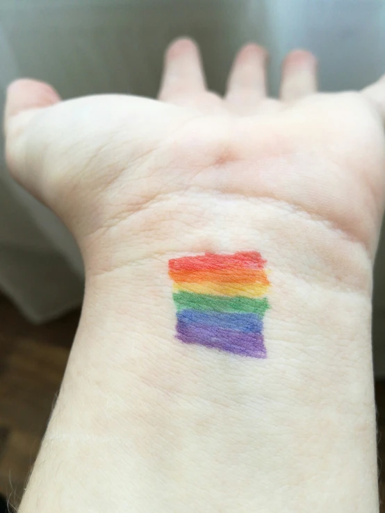 a hand with a small rainbow painted on it