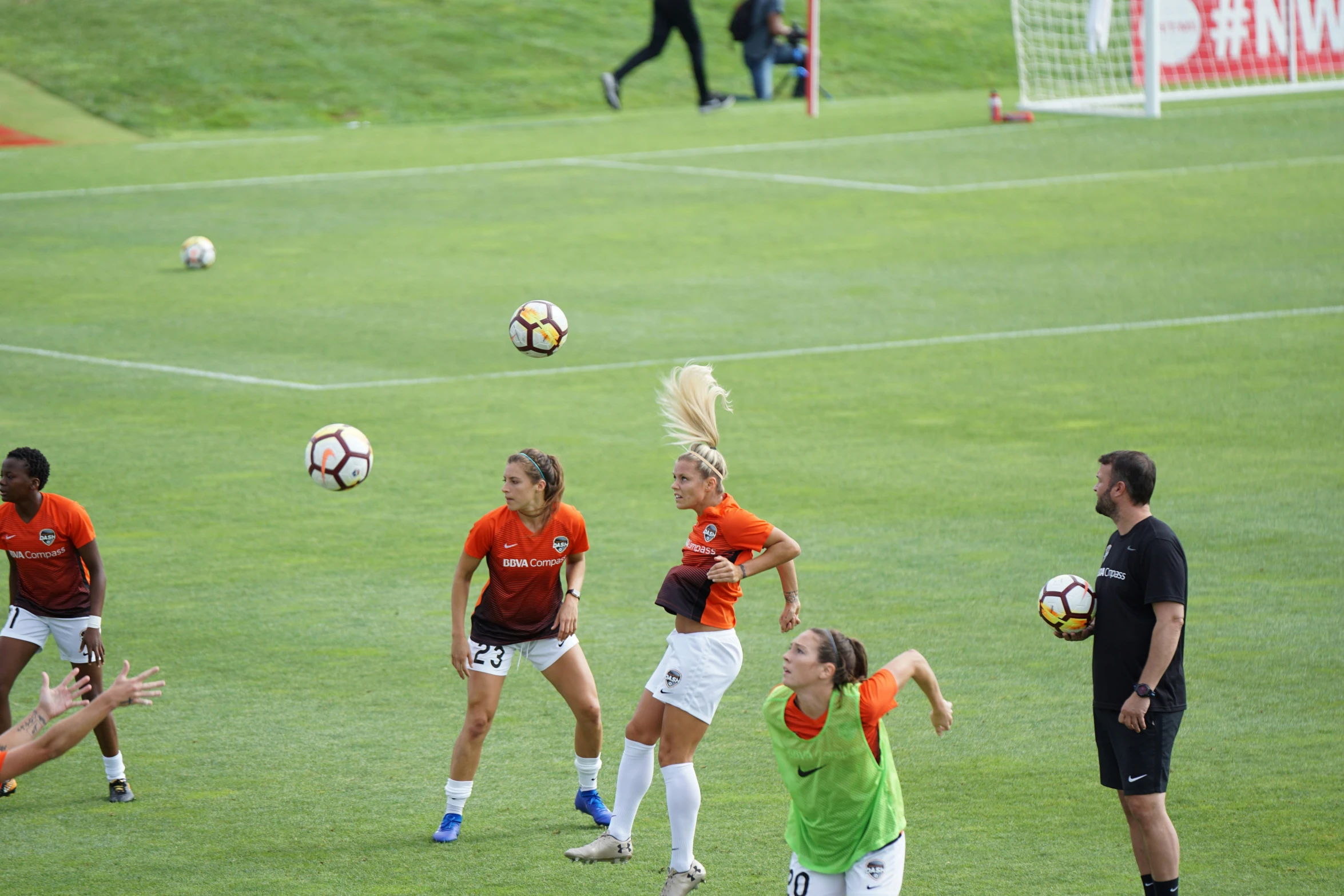 four women on the field playing soccer in a park