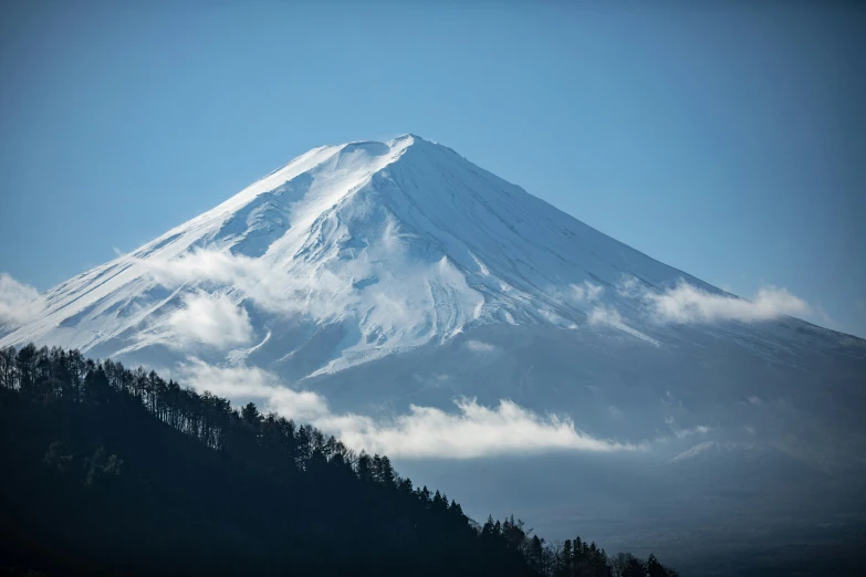 a mountain that is covered in snow with pine trees on the top