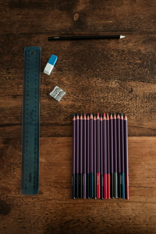 a pile of colored pencils next to a large ruler