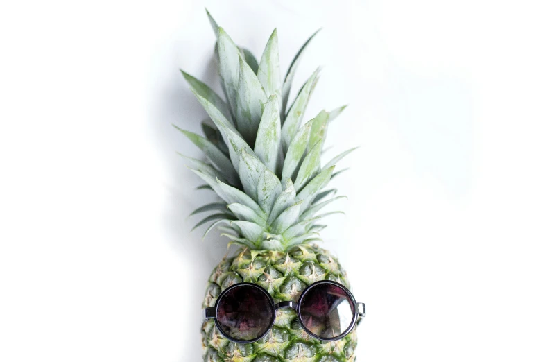 a pineapple wearing sunglasses has a white background