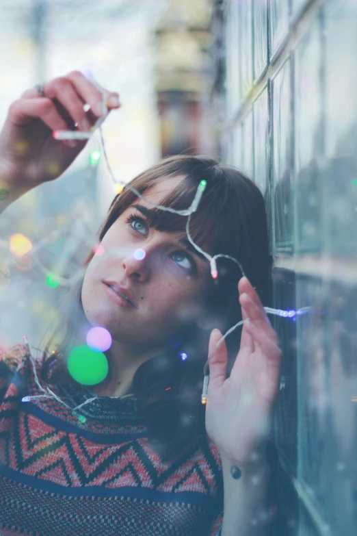 a girl stands against a building as the lights shine brightly