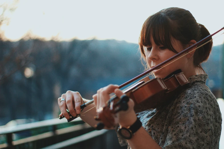 woman in gray shirt playing violin on deck