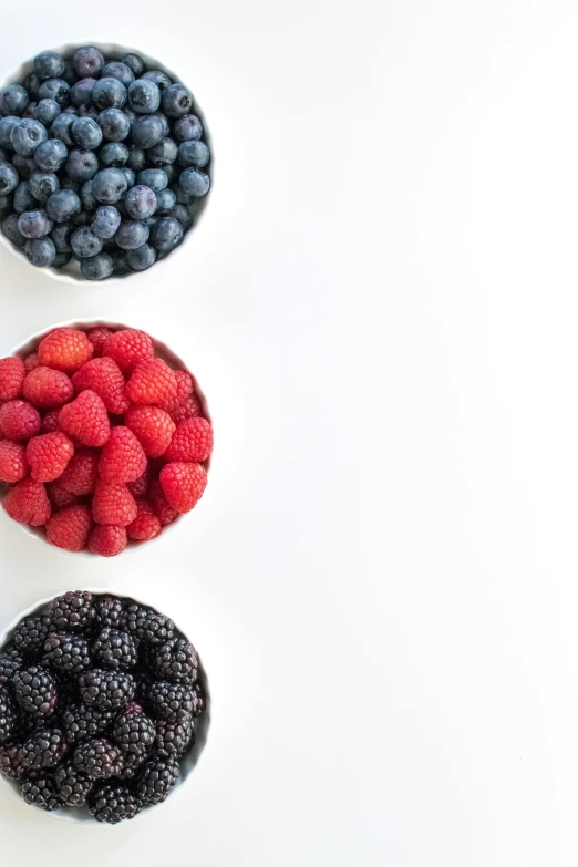 three small bowls of fresh blueberries and raspberries