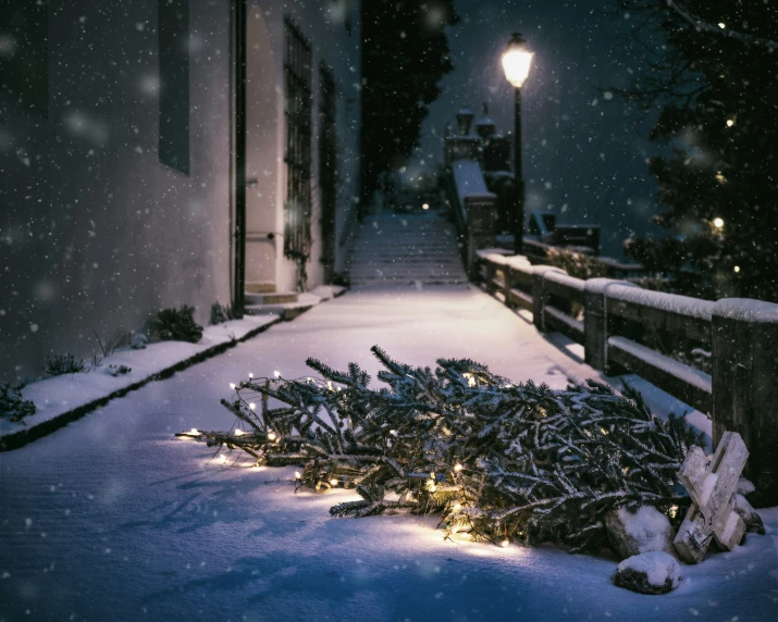 a snowy sidewalk next to a building with lights on