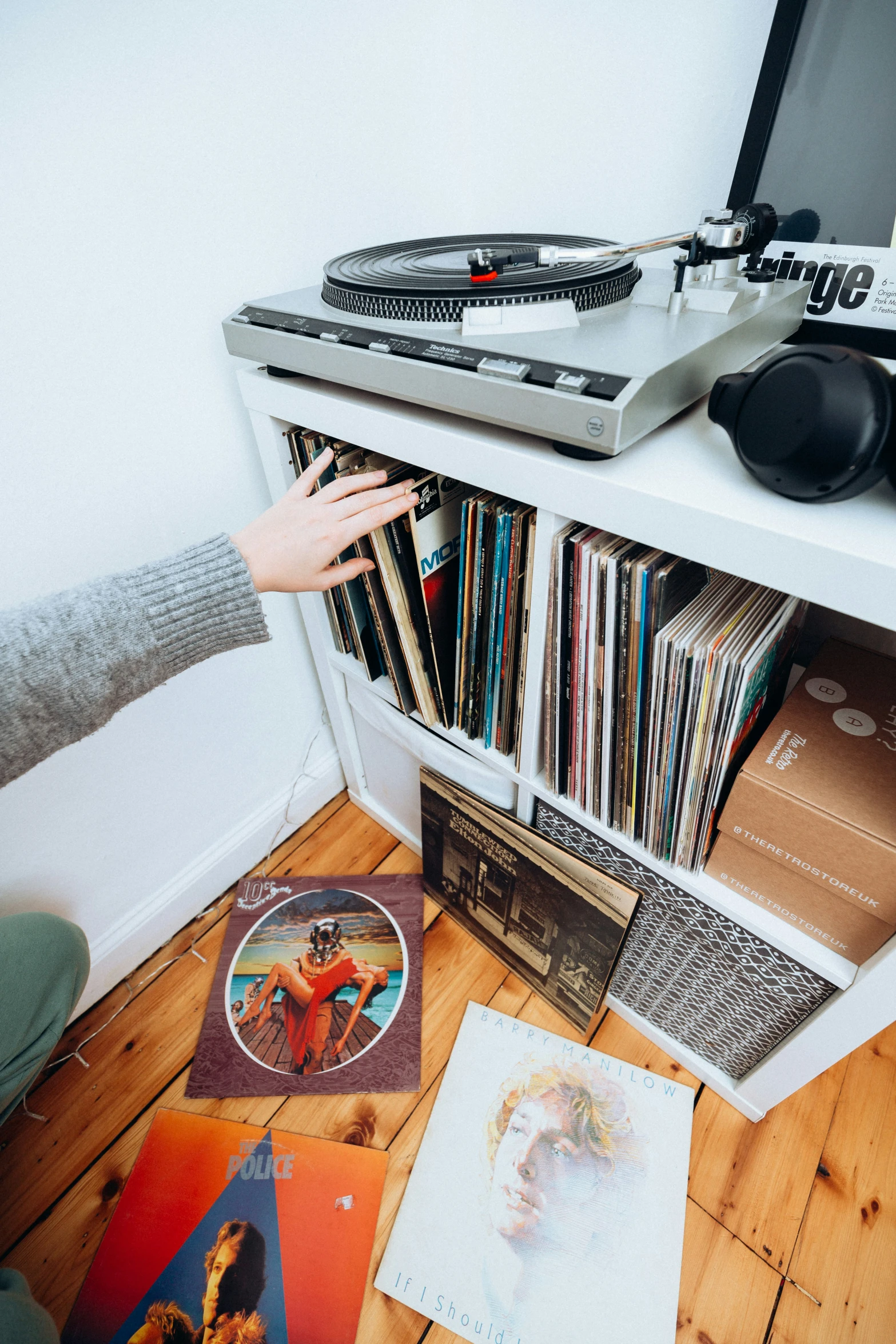 a girl reaches for vinyl records in front of a recordshelf