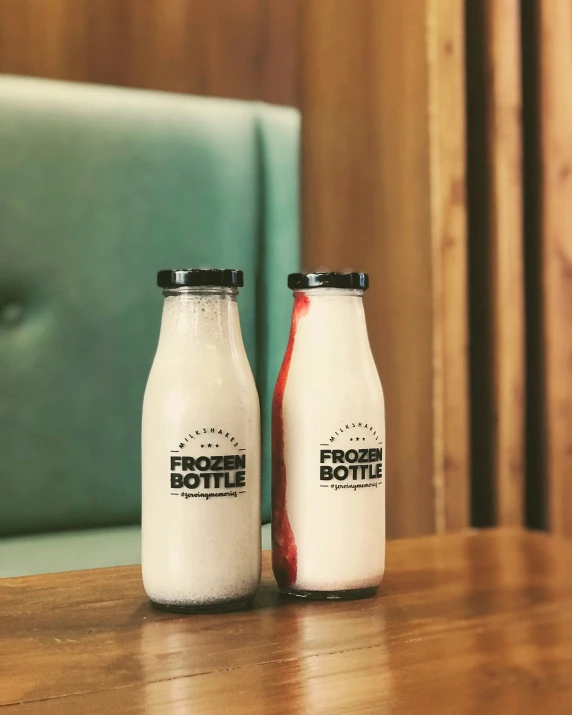 two bottles of yogurt sit on a wooden table