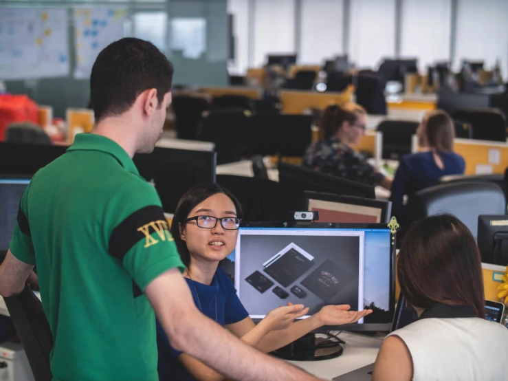 people sitting at tables working on computers in an office