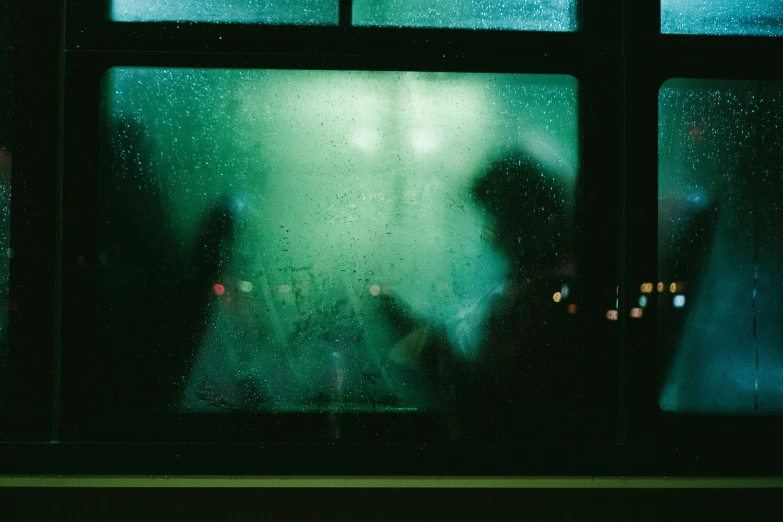 the silhouettes of people are reflected in an open window