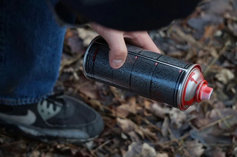 a man holds an empty coca cola can in the middle of leaves