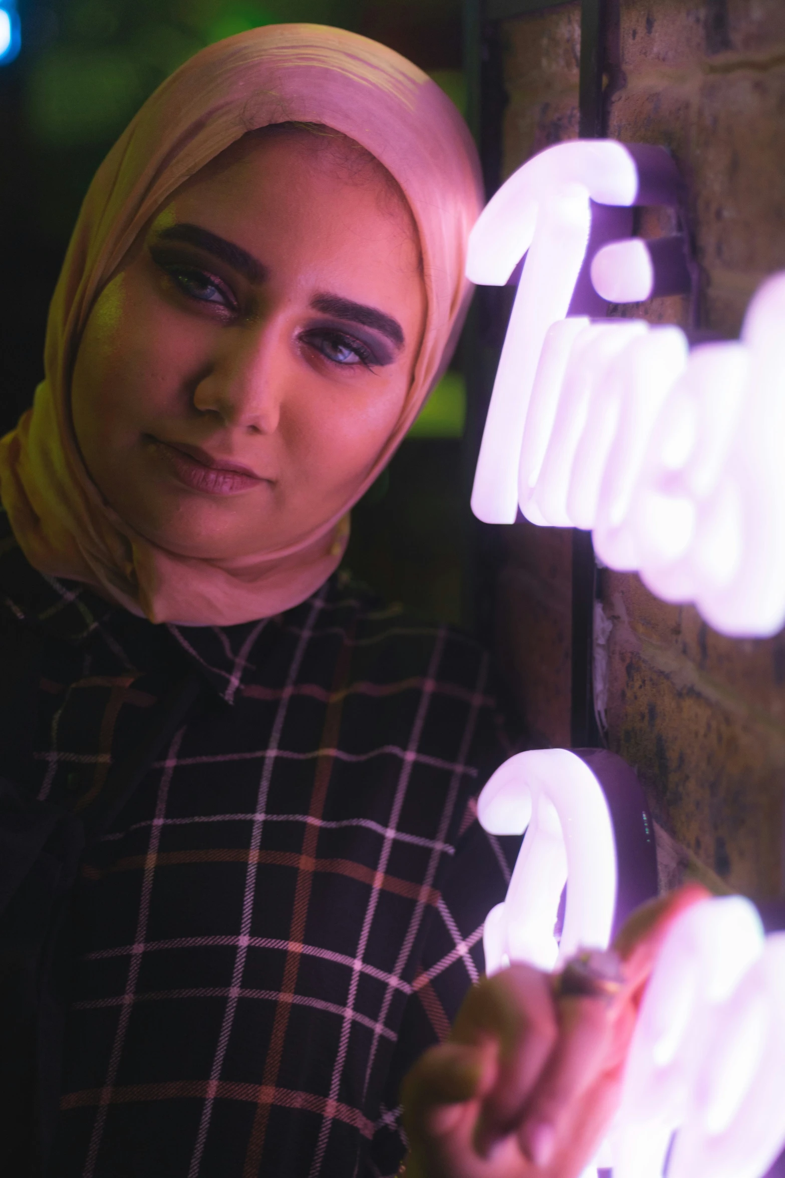 a young woman leaning against the wall holding onto a light that says'friends '