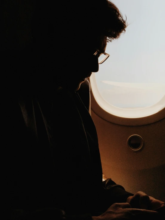 man looking at the screen of his tablet near a window in an airplane