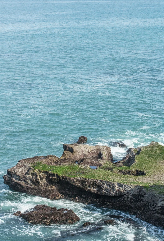 the lone person is on the rocky shore near the ocean