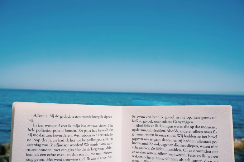 an open book with the ocean in the background