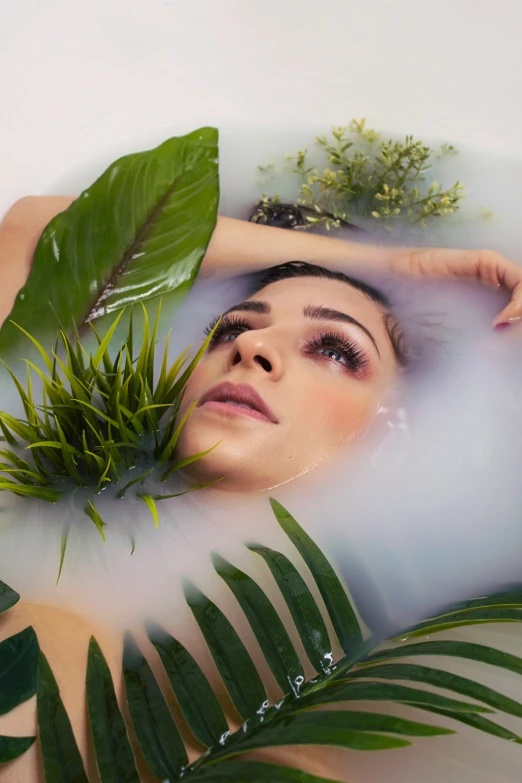 a girl's head is covered with water and greenery