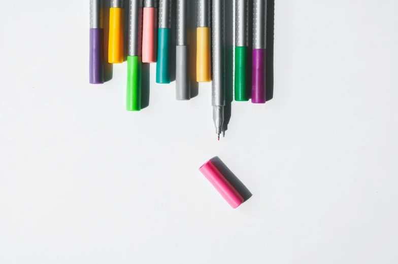 a group of markers and pens laying next to each other