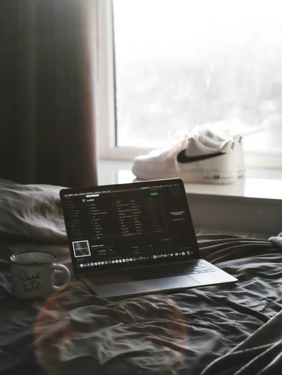 a laptop on top of a bed with the image of a coffee cup