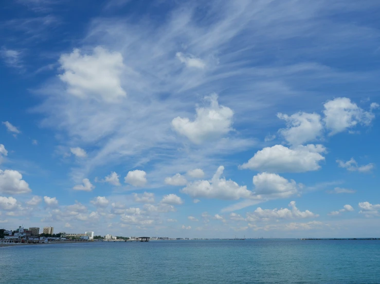 the sky above the water has clouds and some buildings